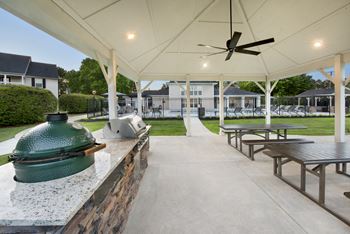 a patio with picnic tables and a grill and a ceiling fan